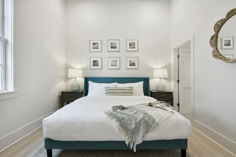 Bedroom 2 with a king bed, teal frame, framed prints and teal lamps on dark nightstands