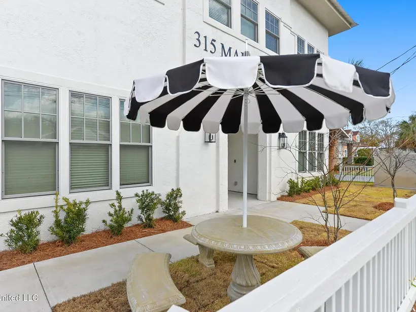 The black-and-white striped umbrella over a stone table beside the building's white stucco wall